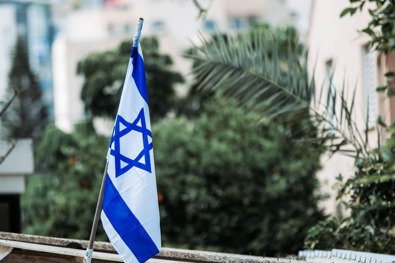 Israeli flag displayed among urban greenery, reflecting national pride and identity.